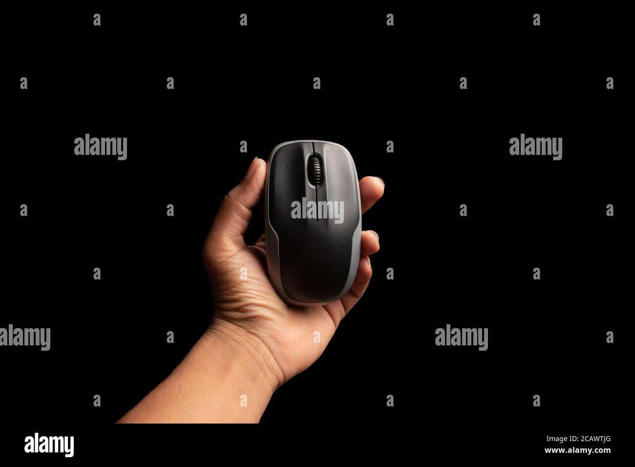 hand holding computer mouse isolated on the black background. Stock Photo