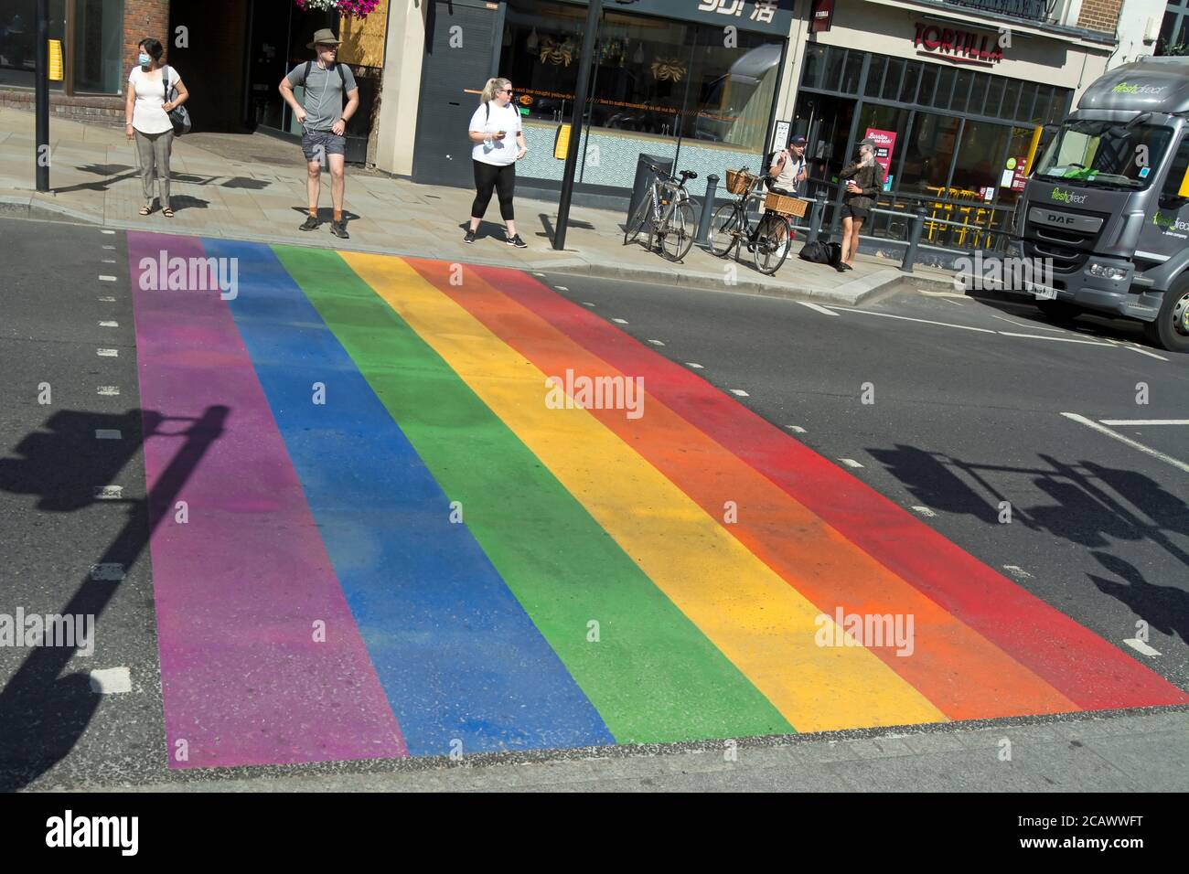 pedestrians wait to cross a rainbow painted, indicating support for lgbtq+ communities, road crossing in richmond upon thames, surrey, england Stock Photo