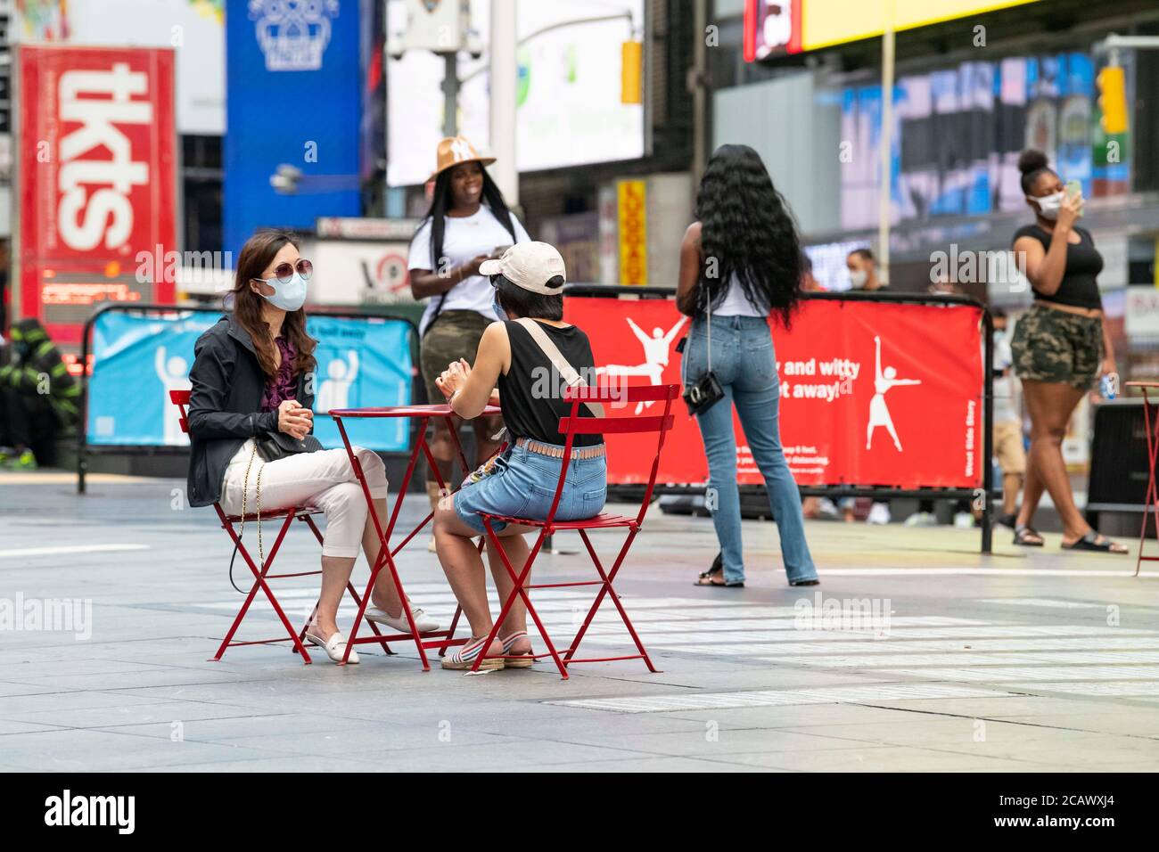 August 08, 2020 Two asian women sit at a table in Times Square wearing