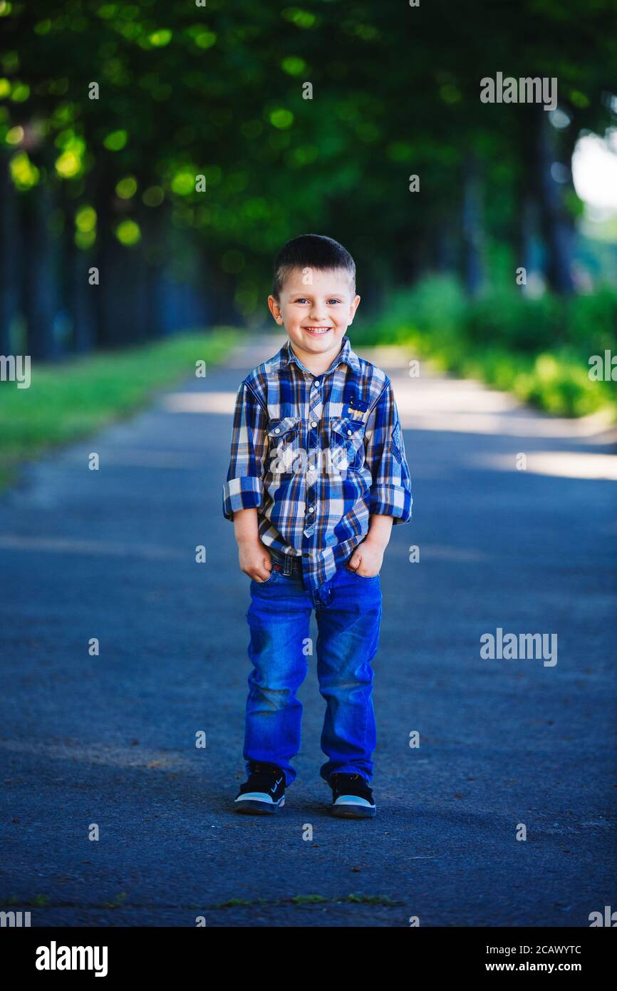 A cute little boy sit is having fun outdoors. stylish child in the ...