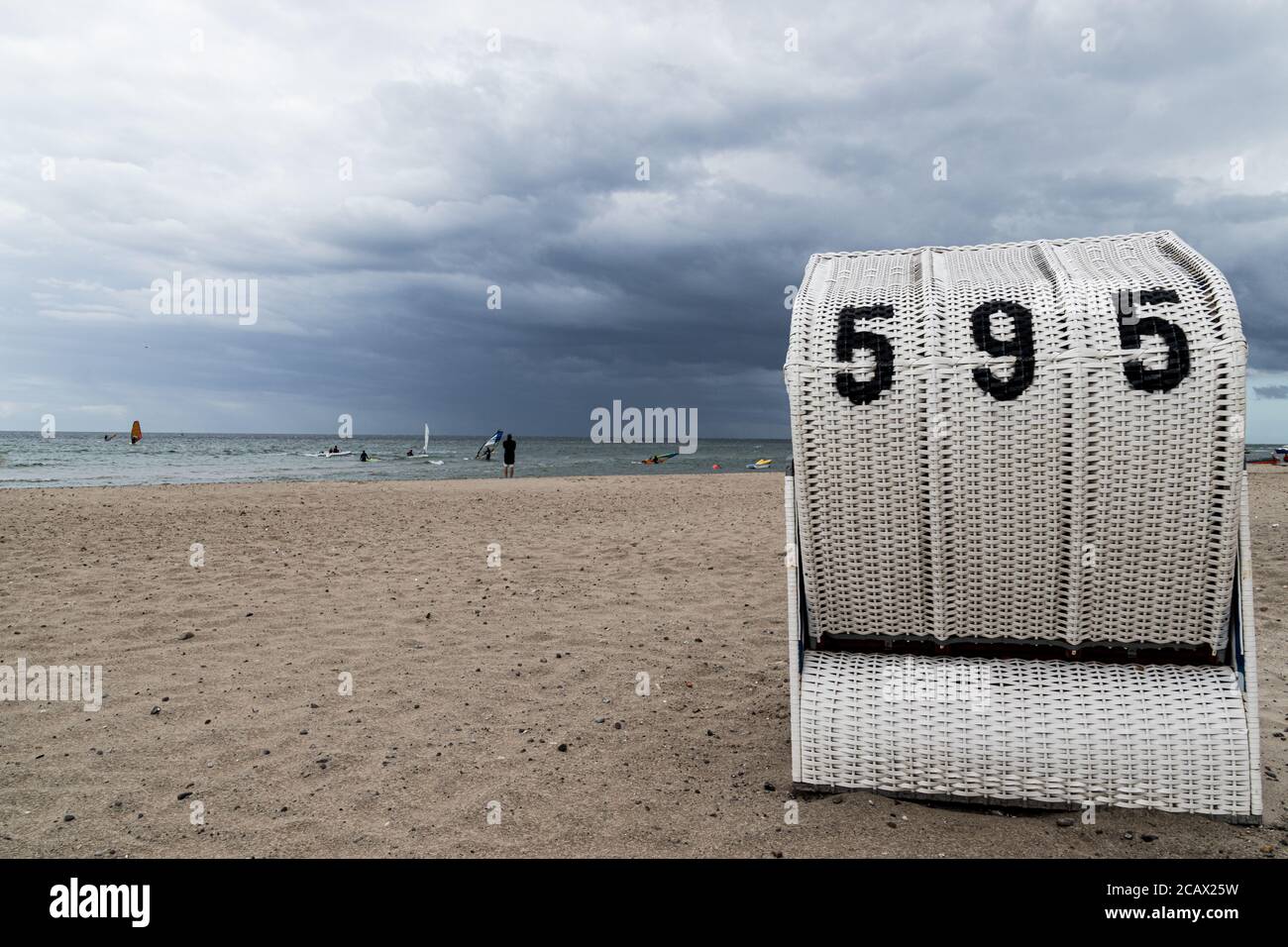 View of one white wicker beach chair on sandy beach at the Baltic Sea in Germany on a cloudy day. Royalty free stock photo. Stock Photo