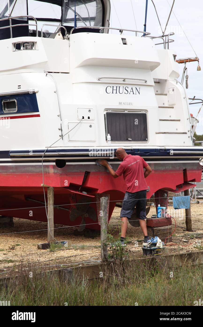 A worker maintains a boat 'Chusan' at Bucklers Hard, Boldre, New Forest