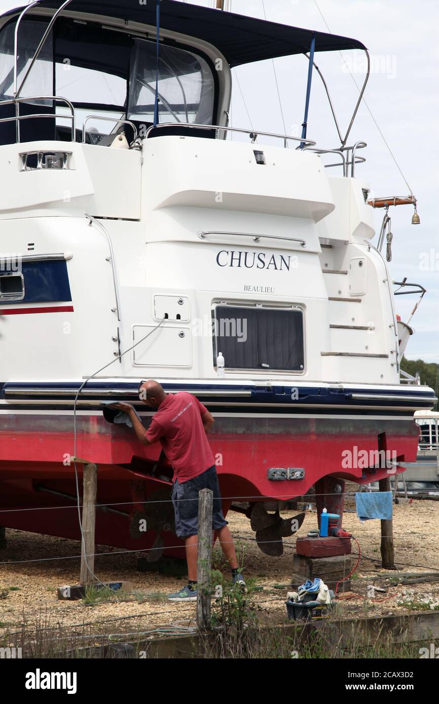 A worker sands a boat hull 'Chusan' at Bucklers Hard, Boldre, New