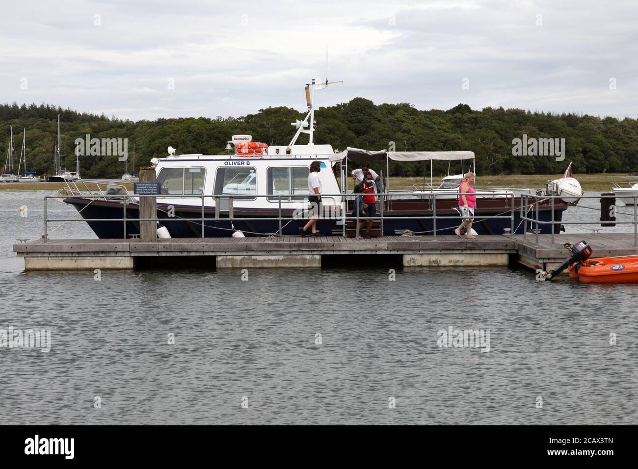 Passengers in facemasks disembark Oliver B boat, Beualieu River cruise at Bucklers Hard, New Forest, Hampshire, England, UK Stock Photo