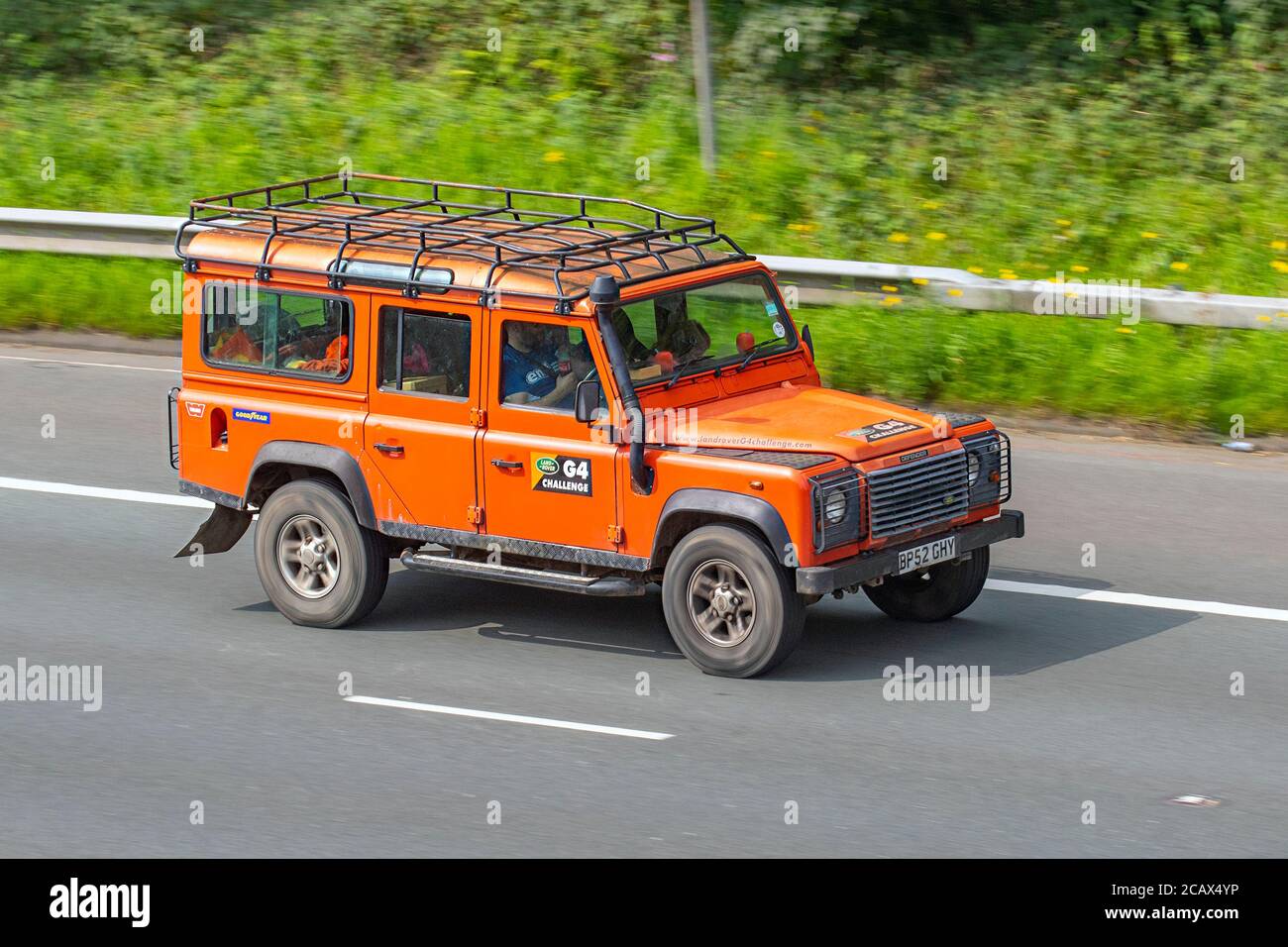 2003 orange Land Rover Defender 110 TD5 County G4 Challenge; a global adventure competition,Vehicular traffic moving vehicles, 4x4 cars driving vehicle on UK roads, motors, motoring on the M6 motorway highway network. Stock Photo