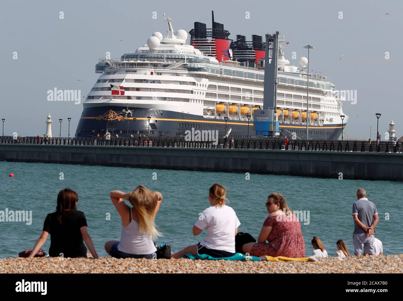People Enjoy The Hot Weather On The Beach As The Cruise Ship Disney Magic Ferry Is Seen Docked In The Port Of Dover Amid The Coronavirus Disease Covid 19 Outbreak In Dover Britain