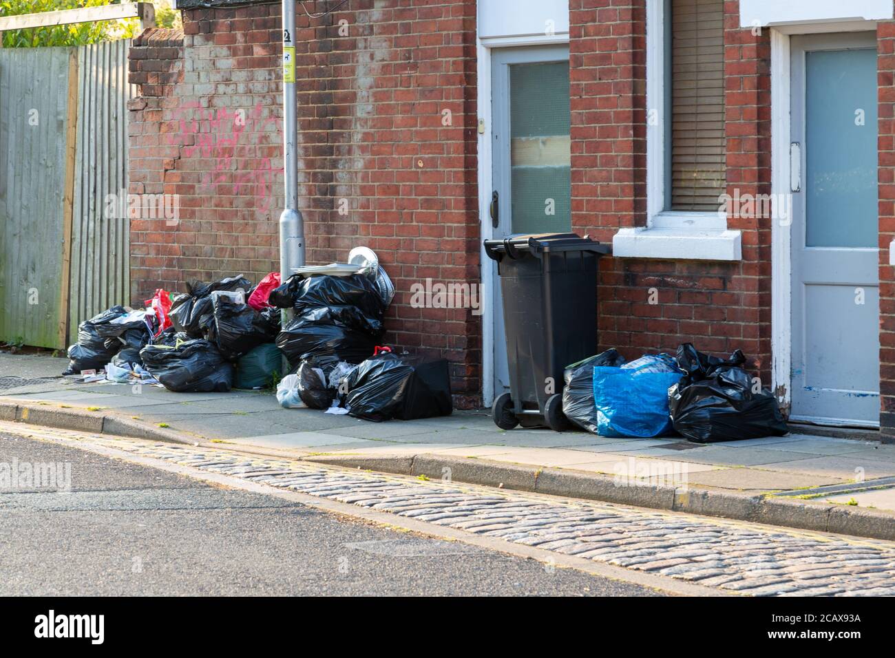 Plastic bin bags full of rubbish outside a home ready for collection by bin men on bin collection day Stock Photo