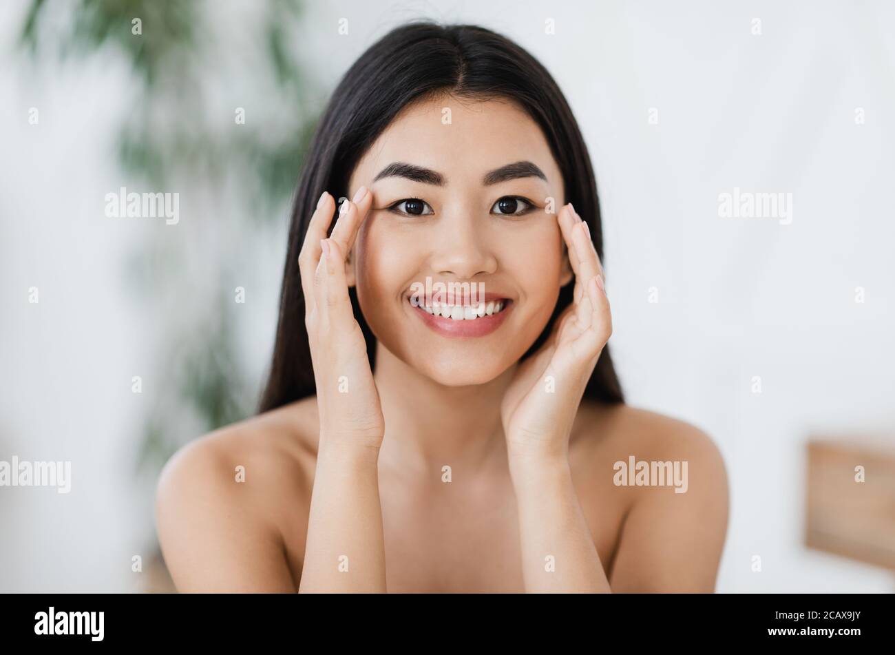 Attractive smiling asian woman rubbing massaging her eye zone Stock Photo