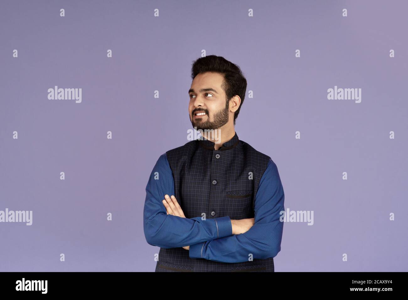 Positive Indian guy standing with crossed arms on lilac background ...