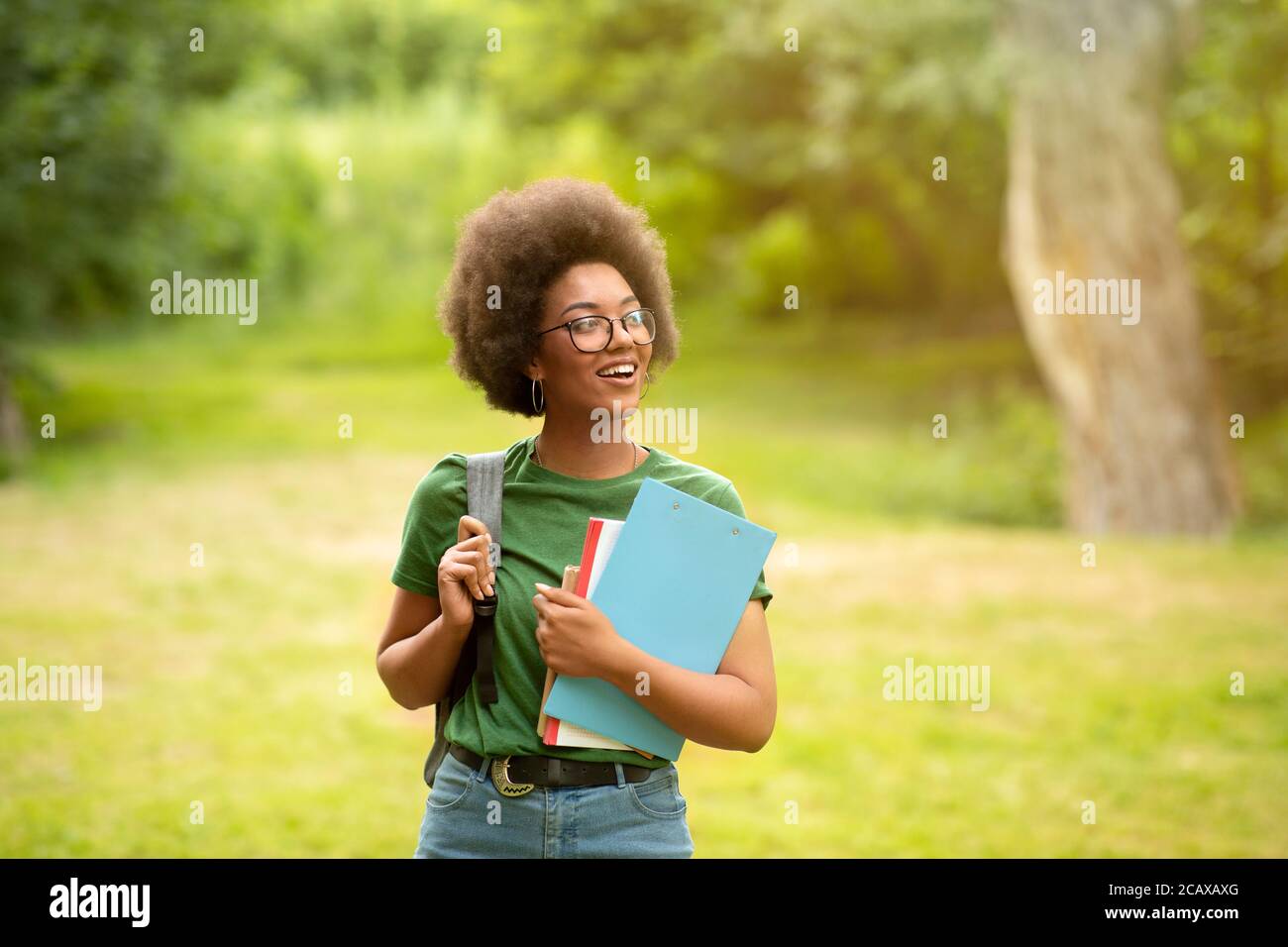Black millennial student girl with backpack and workbooks posing outdoors at campus Stock Photo