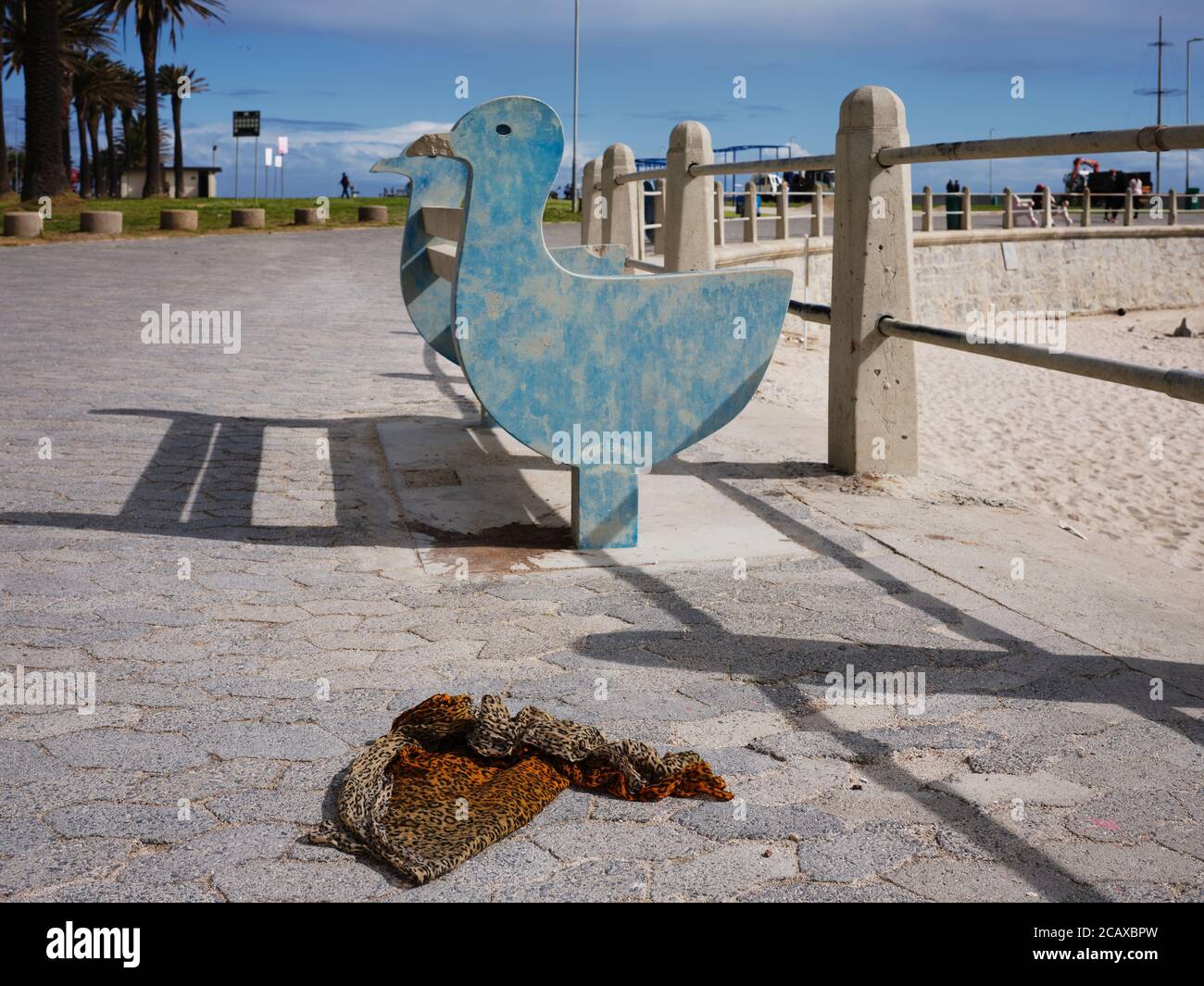 Piece of leopard print clothing on the pavement in front of bench on the Sea Point Promenade in Cape Town. Stock Photo