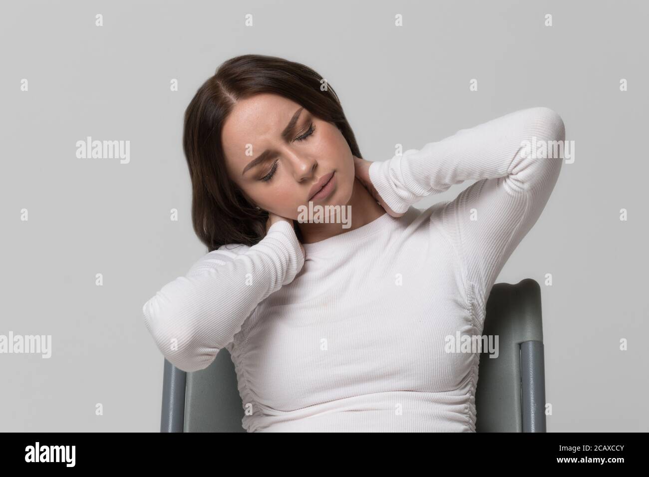 Closeup portrait of unhealthy female massages painful neck pain and back. Cervical arthritis, osteochondrosis, diseases of the musculoskeletal system Stock Photo