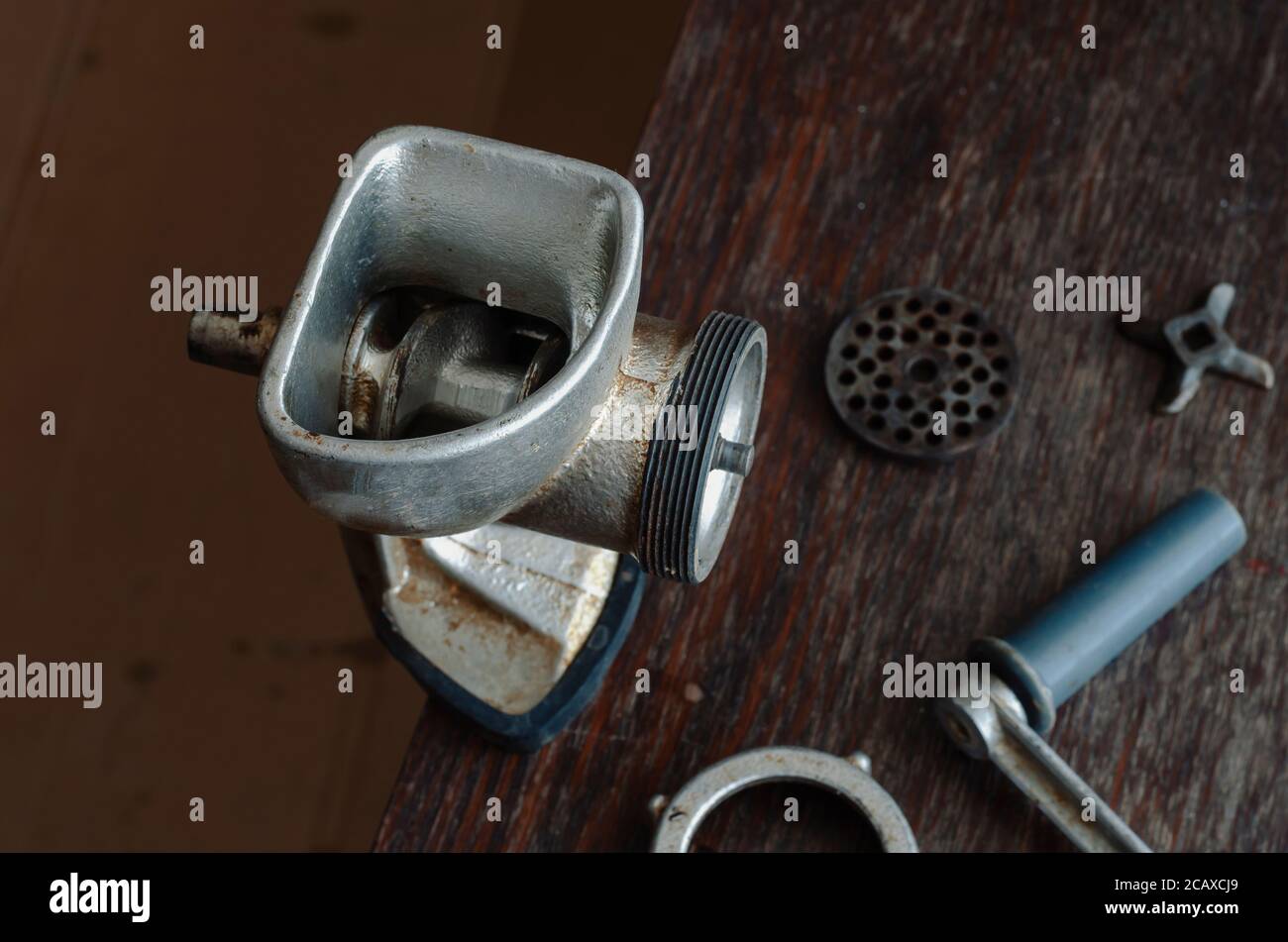 Disassembled manual vintage meat grinder on wooden table. Hand tool for