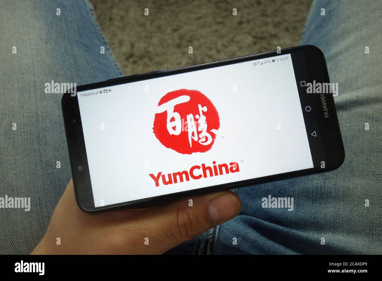 Man holding smartphone with Yum China restaurant company logo Stock Photo