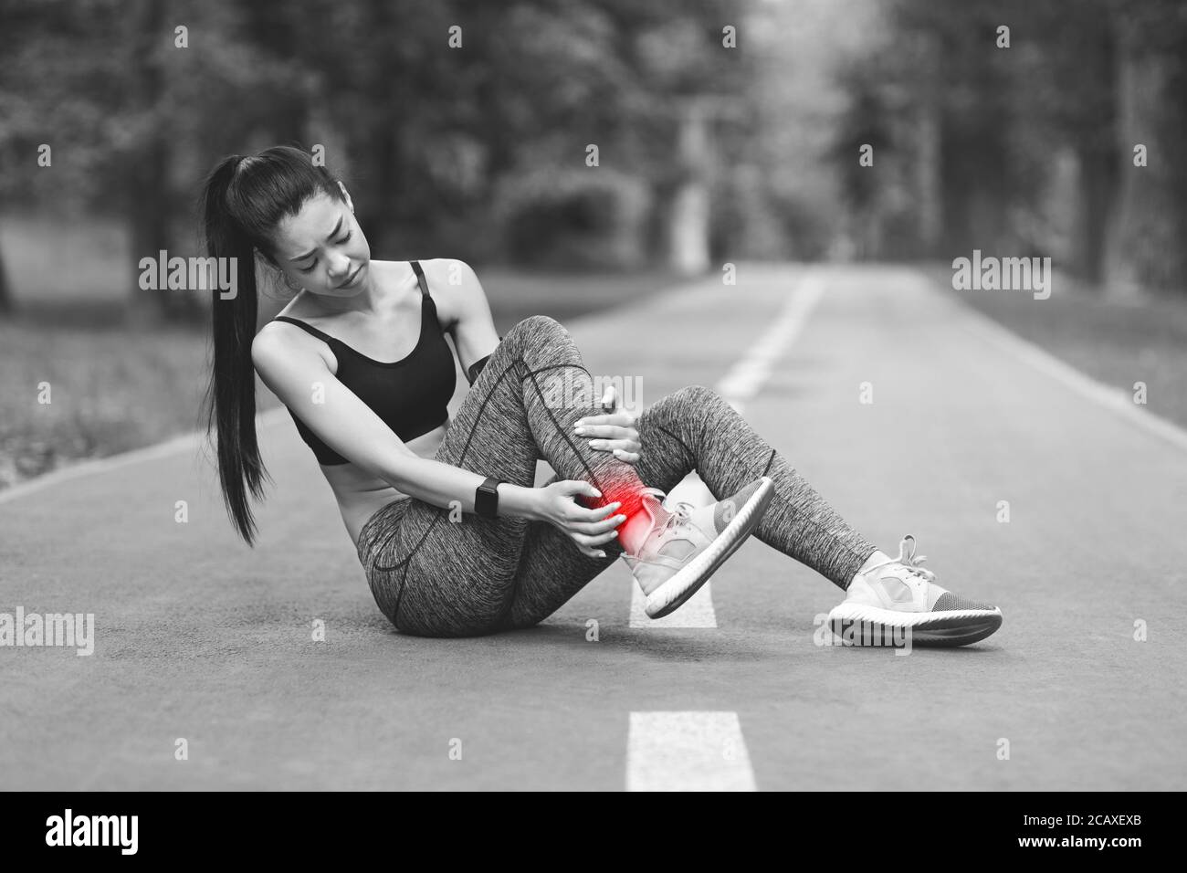 Asian Girl Having Ankle Pain After Jogging Outdoors, Massaging Red Sore Spot Stock Photo