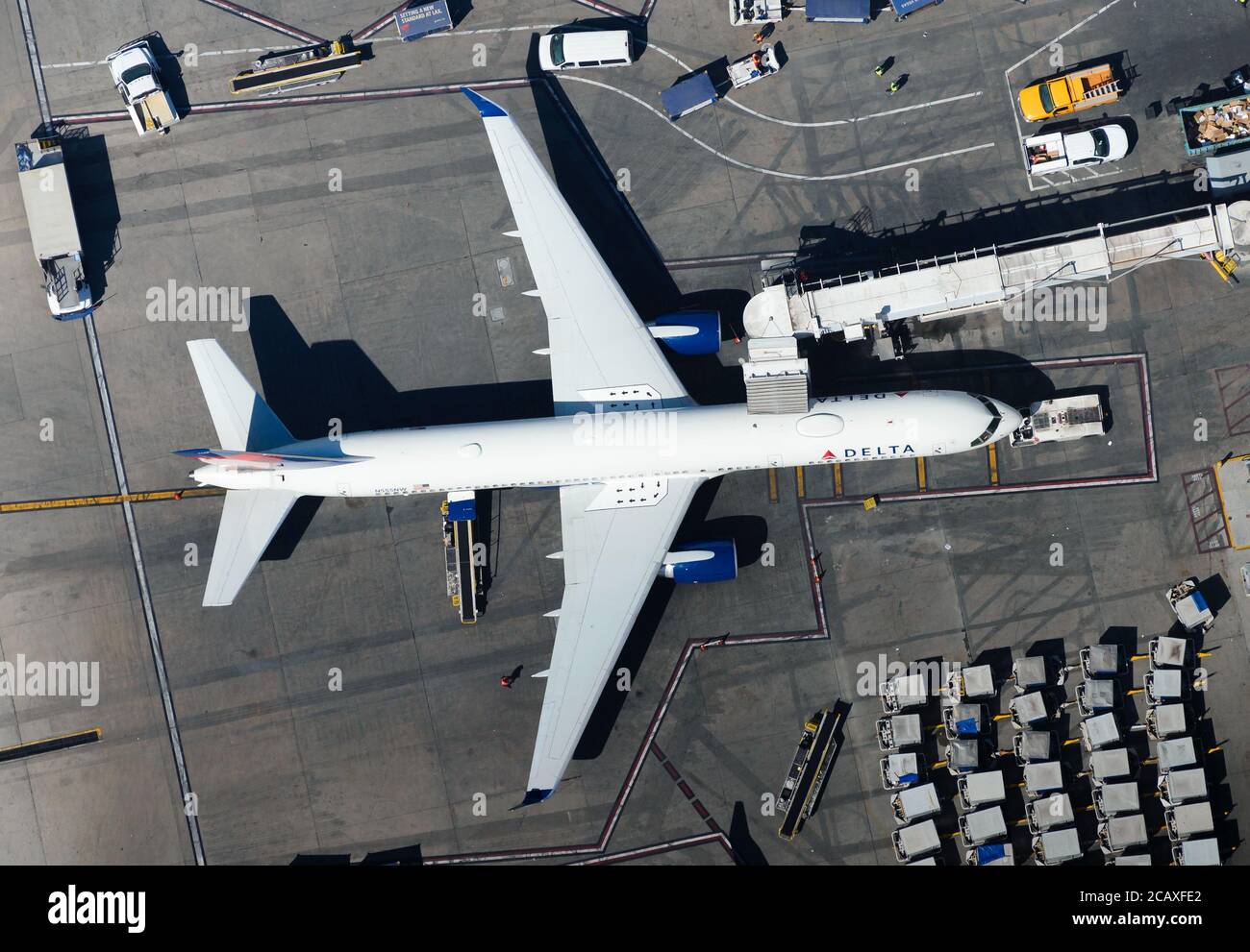 Delta Airlines Boeing 757 at LAX airport connected to jet bridge aerial view. Ground equipment visible around Delta B757 / 757-200. Stock Photo