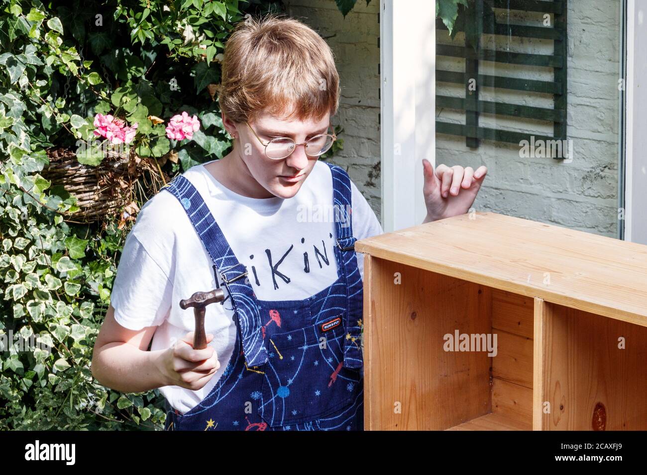 20-year old Caucasian young woman constructing a wooden bookcase at home, London, UK Stock Photo