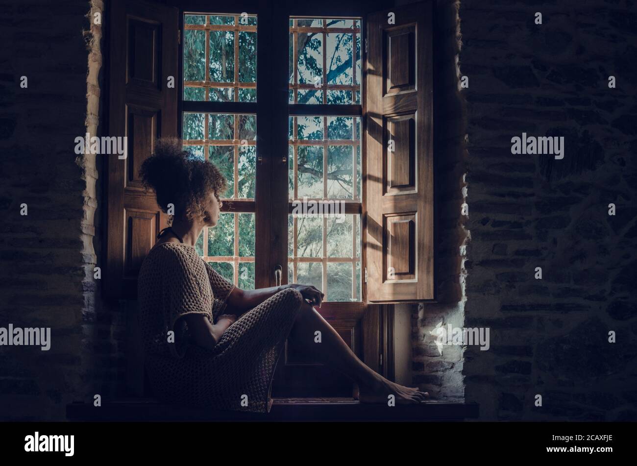 Black woman looking through the window during Coronavirus confinement Stock Photo