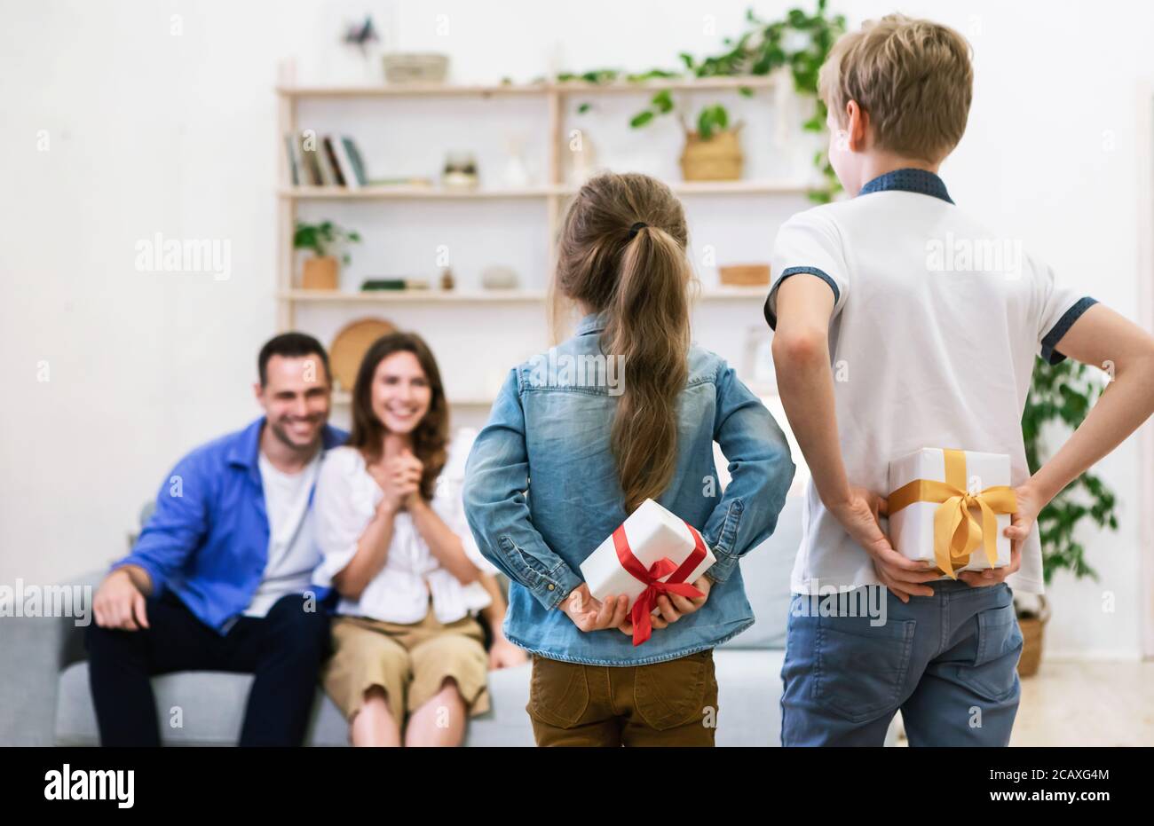 Children Giving Gifts To Their Happy Parents At Home Stock Photo