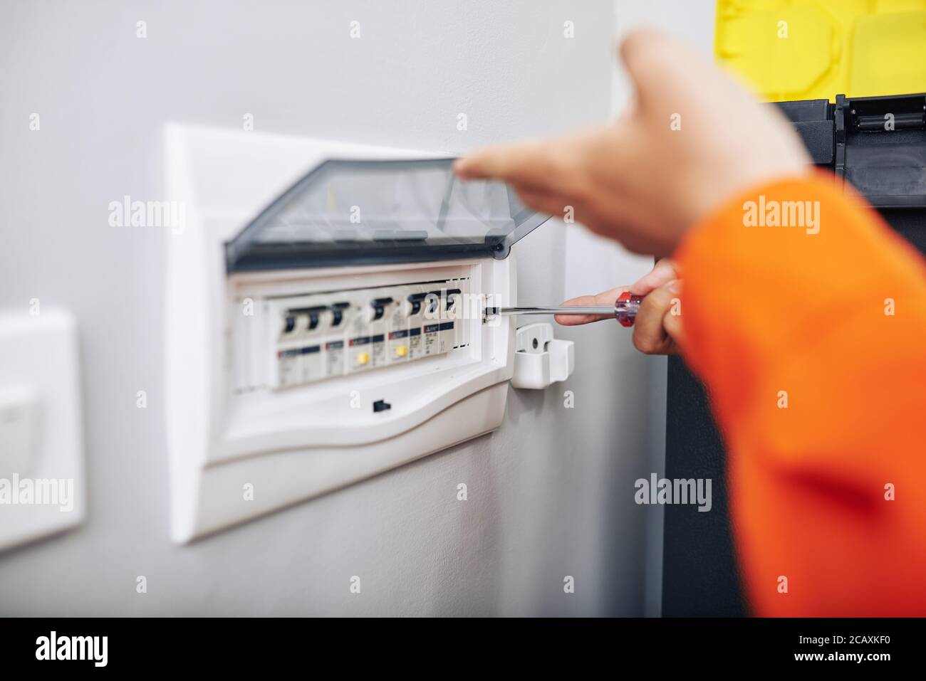 Electrician installing panel with electric meter in apartment of customer Stock Photo