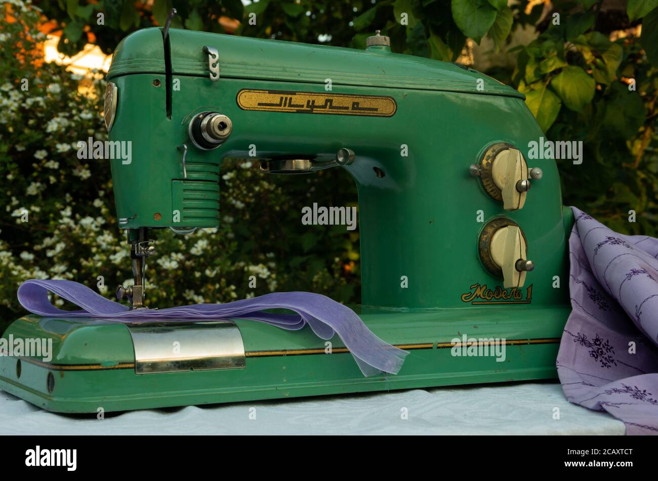 Green old, retro green sewing machine with purple fabric, finger job