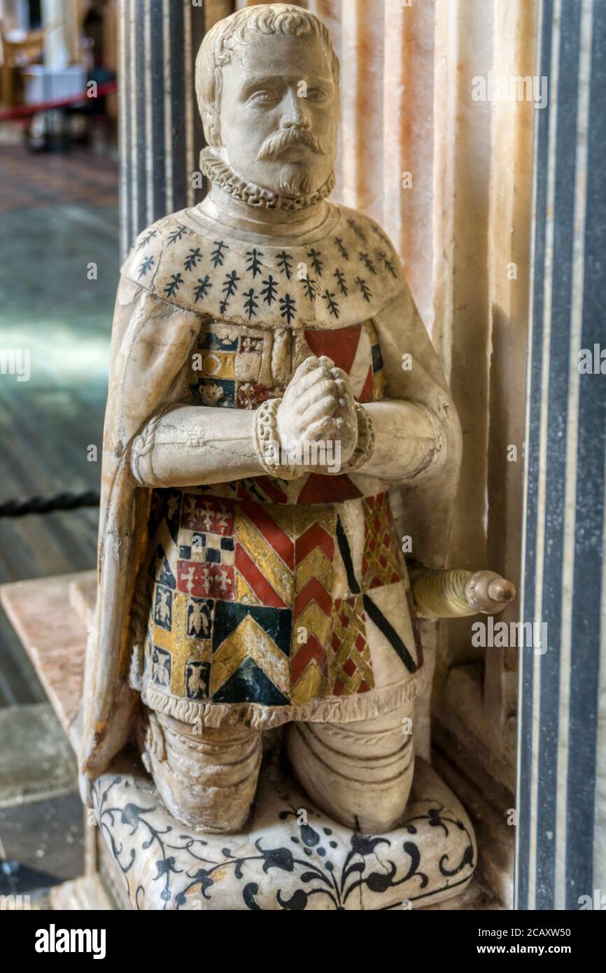 Carved mourner beside 16th century tomb of the 9th Lord Cobham, Sir George Brooke, & his wife in St Mary's church, Cobham, Kent. Shows son William. Stock Photo