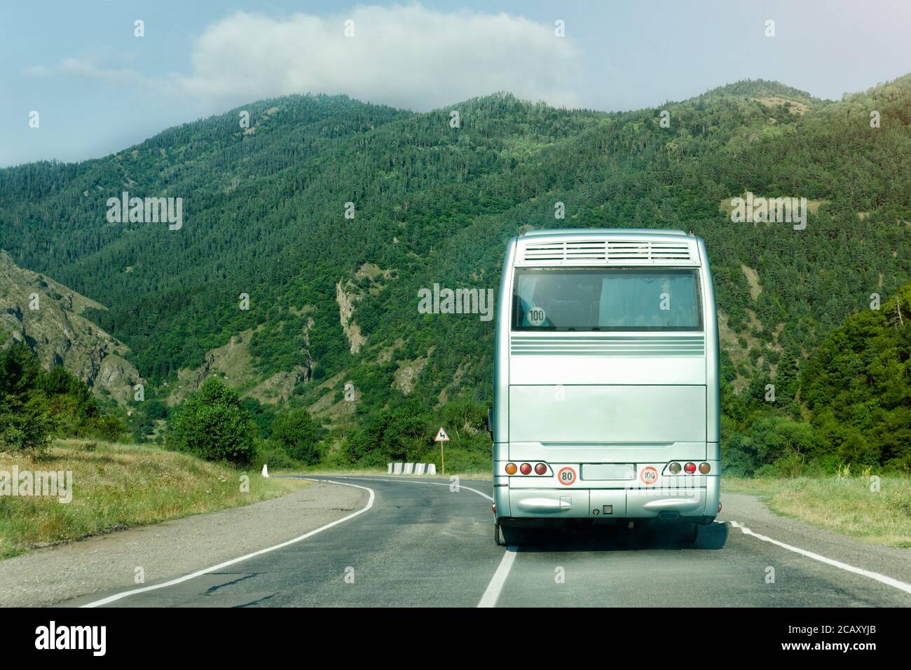 Tourist bus on the road among the green mountains. Back view Stock ...