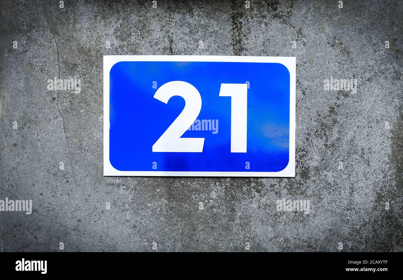 21, number twenty-one, blue number plate on graded gray background. Stock Photo