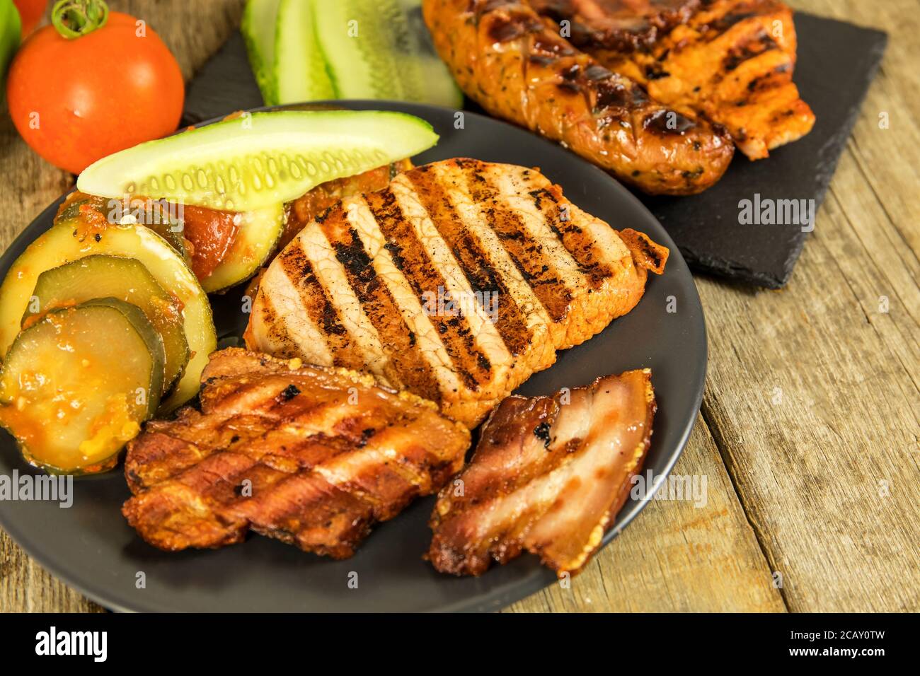 Grilled sausage and pork chops. Wooden background. Grilled meat
