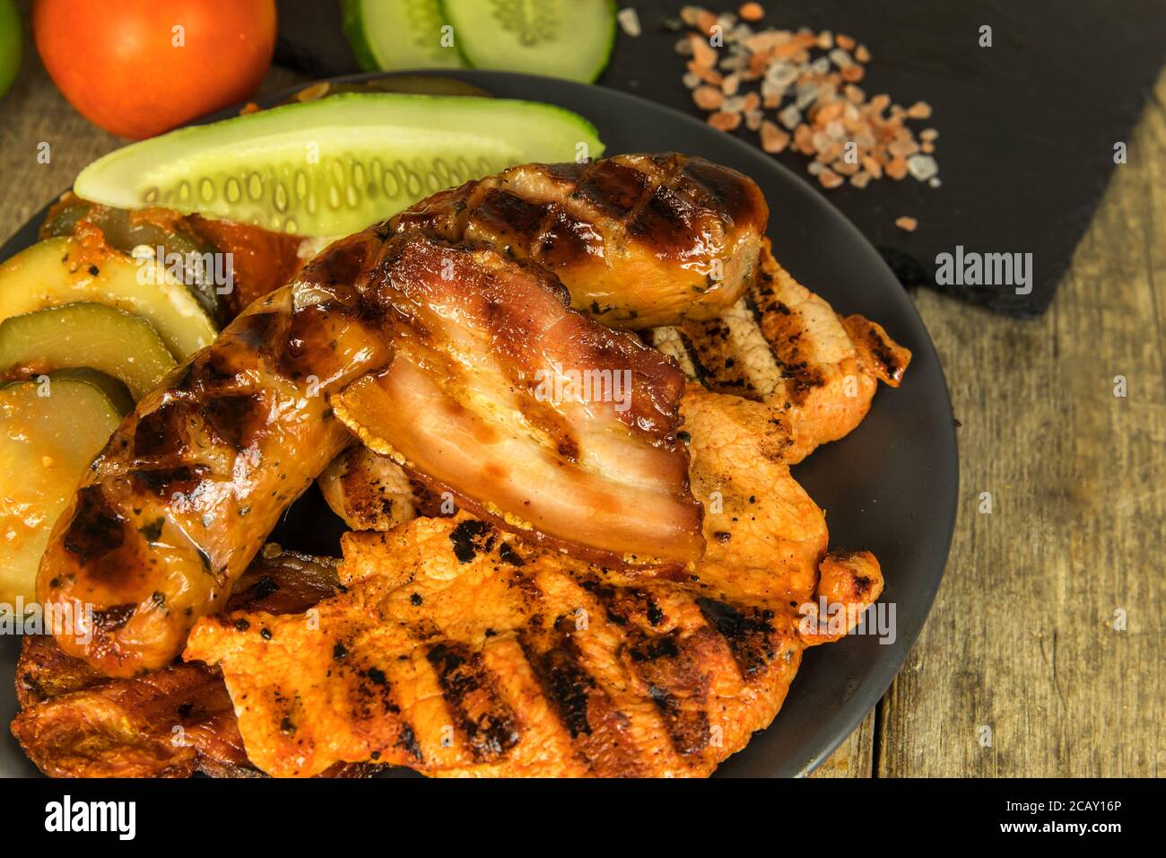 Grilled sausage and pork chops. Wooden background. Grilled meat