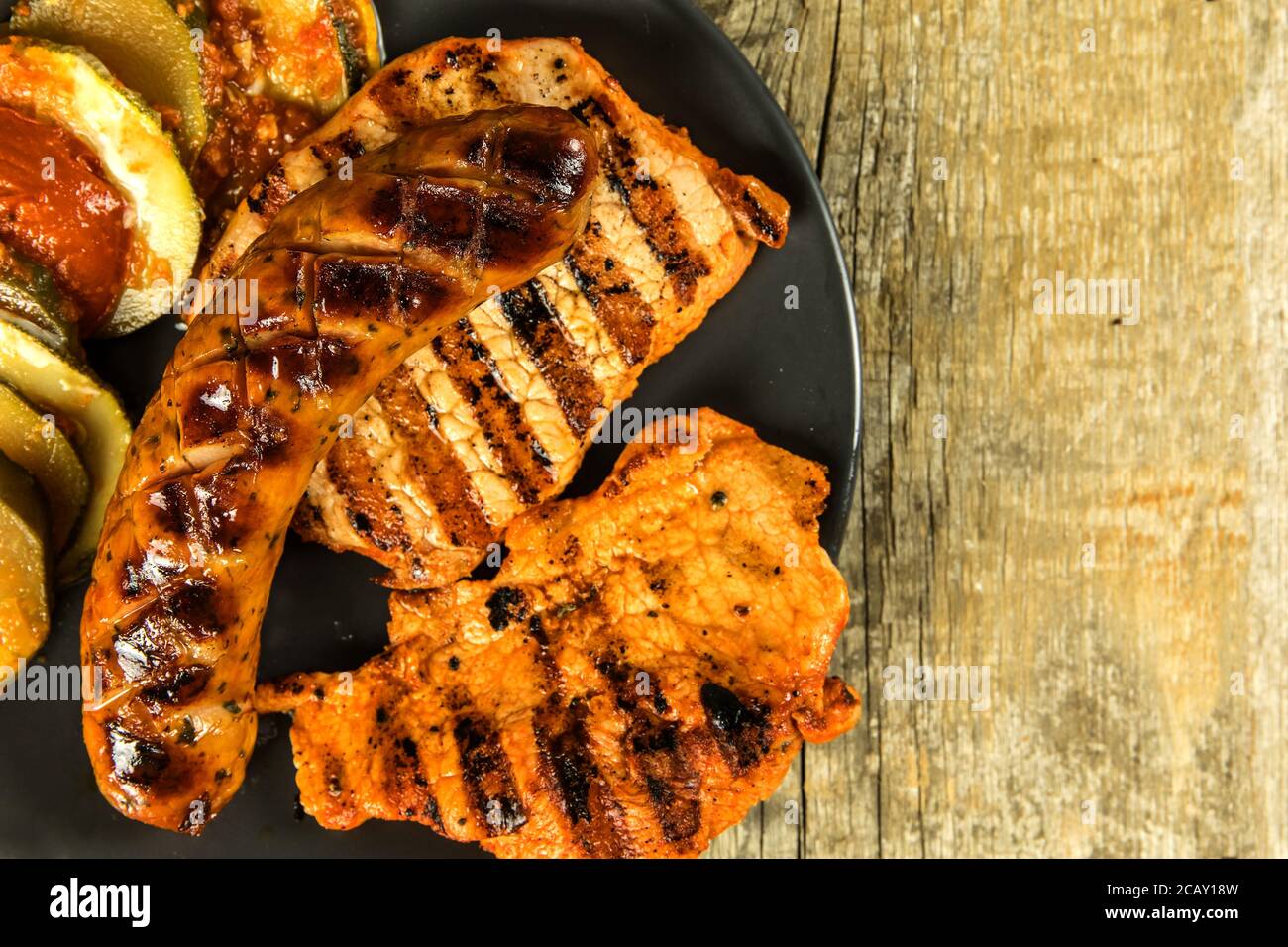 Grilled sausage and pork chops. Wooden background. Grilled meat