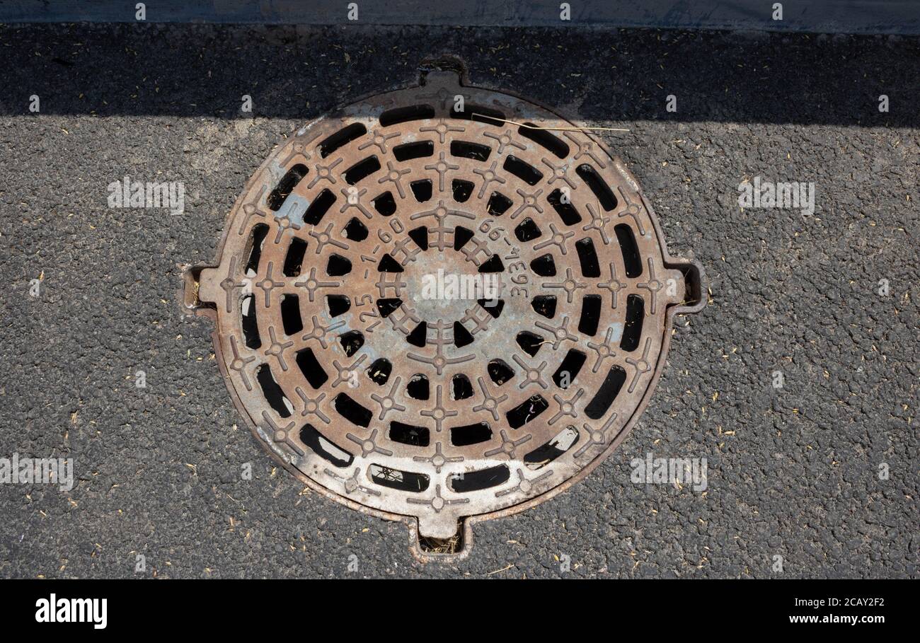 Round grating of the sewer manhole on the road Stock Photo