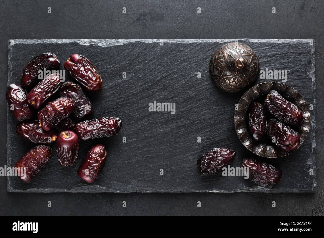 Dried dates on black slate background. Top view with copy space for