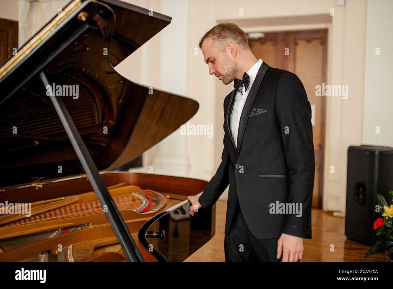 young caucasian musician man in suit stand next to piano, professional