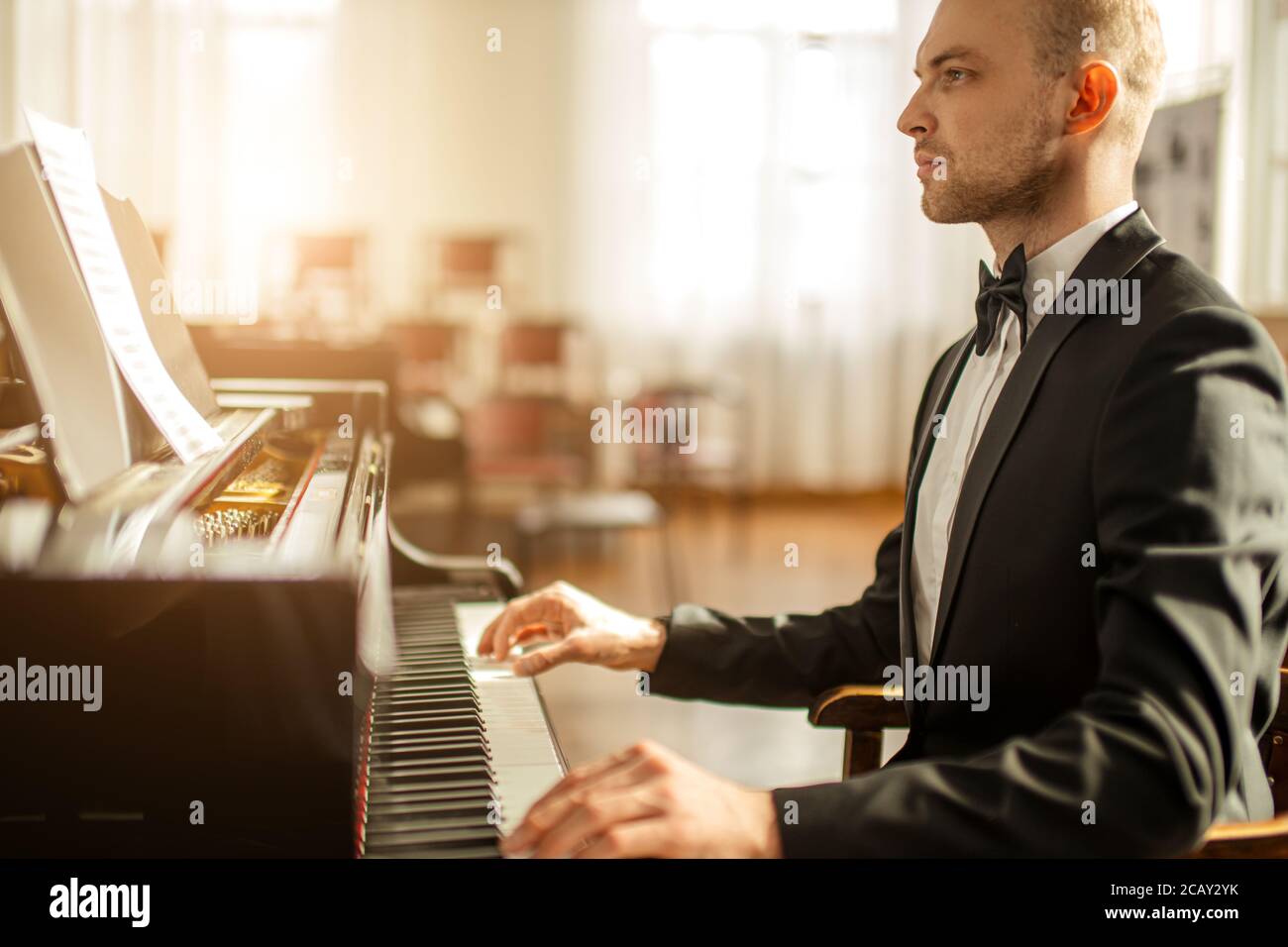 talented young caucasian pianist man practicing, perform awesome music. musician in formal elegant suit play piano Stock Photo