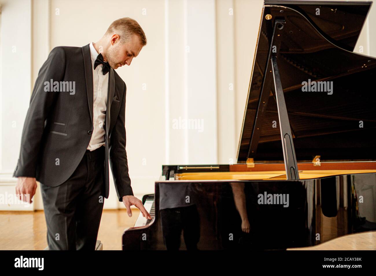 young caucasian guy in formal suit play piano before performance on a stage. conservatory, music, classical instruments concept Stock Photo