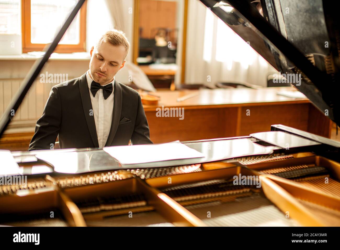 young handsome caucasian man in formal elegant suit gracefully play piano. professional pianist perform classic music Stock Photo
