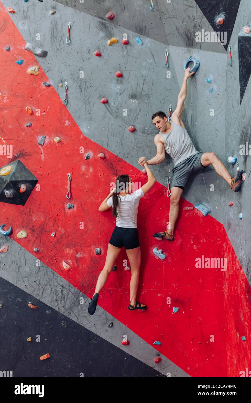 Strong man trying to lift climbing girl. Hand with tense muscles. Man attempting to help woman without experiment. Stock Photo
