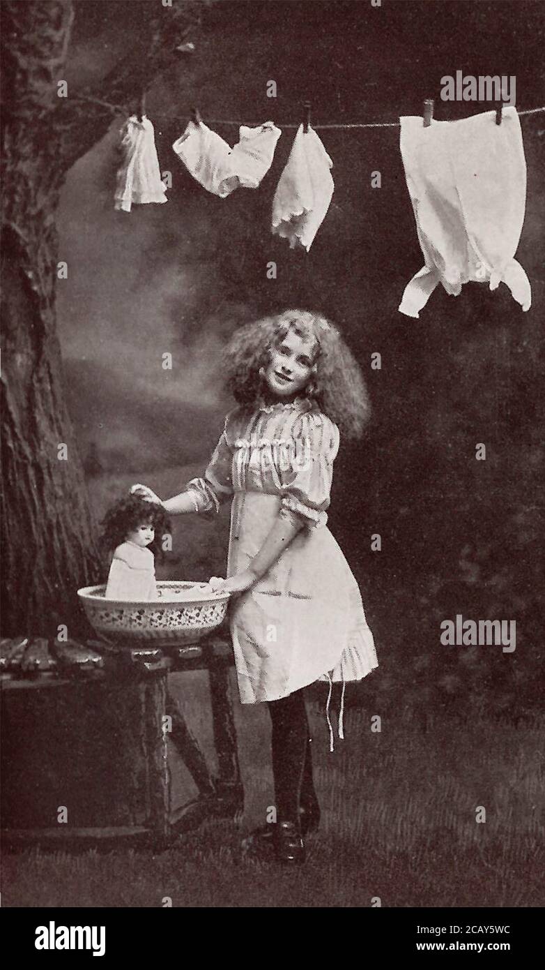Child gives doll a bath; 1908; from a post card from the time period Stock Photo