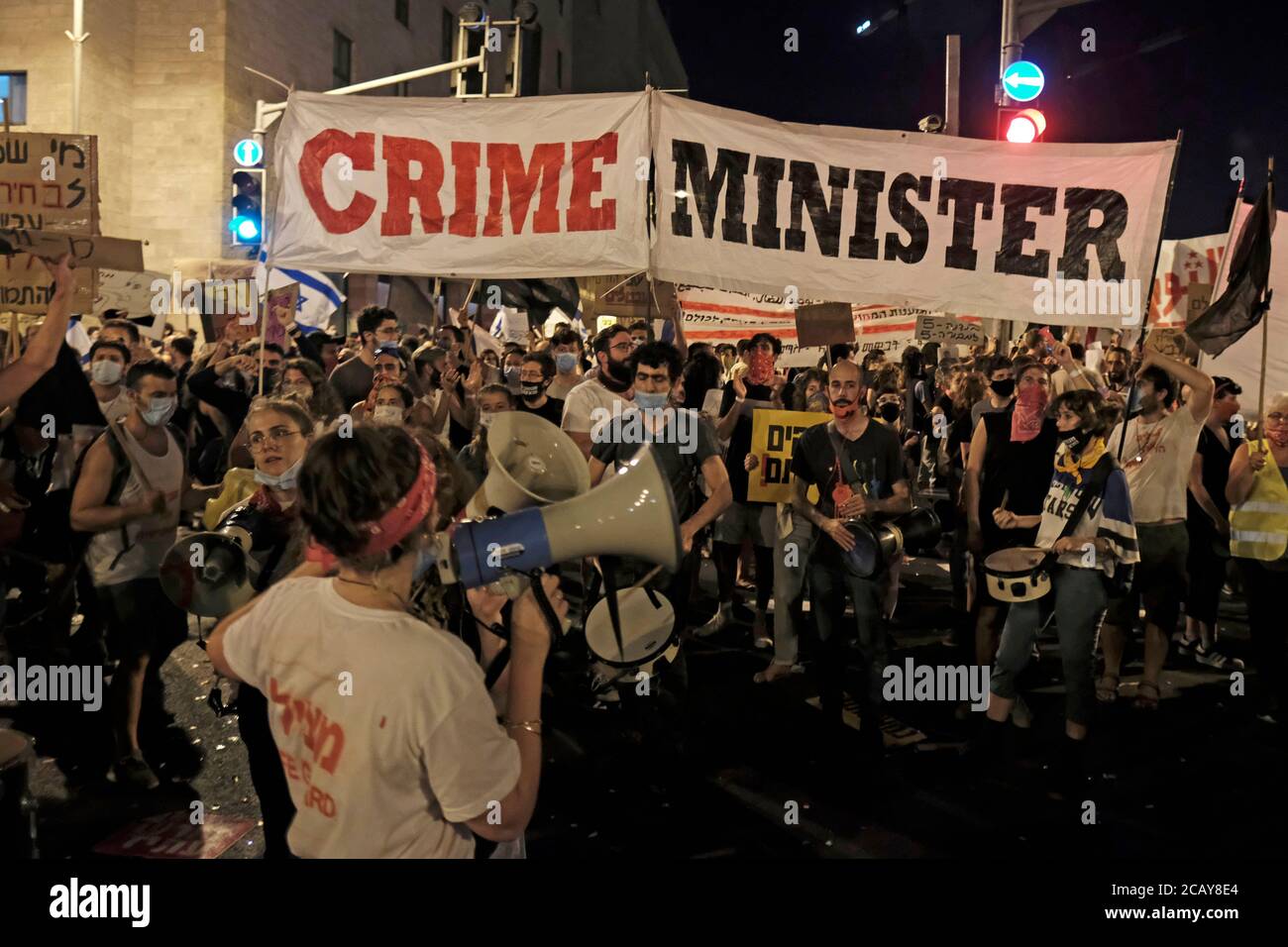 Protesters hold up a large banner which reads 'Crime Minister' and shout slogans during a demonstration attended by over 15,000 people gathered outside the Prime Minister's official residence on August 08, 2020 in Jerusalem, Israel. Israelis have taken to the streets in almost daily demonstrations calling for Netanyahu's resignation over his corruption charges, accused mismanagement of the coronavirus crisis and his assault on democracy. Stock Photo
