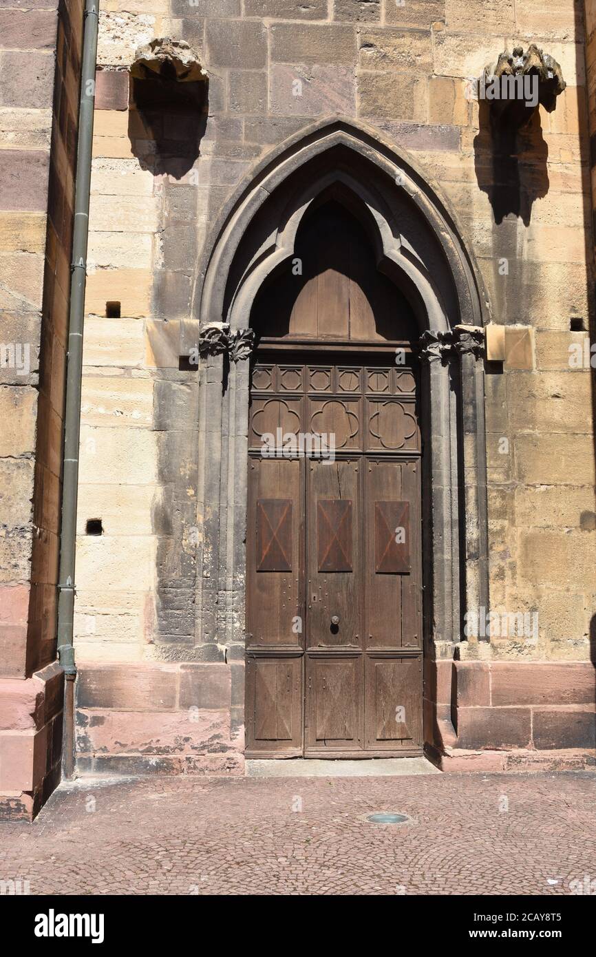 Old heavy wooden door in Gothic architectural style to enter St. Martin's Church in French town Colmar. Stock Photo