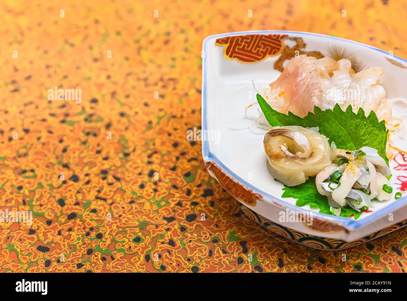 Raw sashimi high-class japanese cuisine of fresh Sayori needlefish, Madai seabream and Hirame halibut in a dish plate with Gracilaria red algae Stock Photo