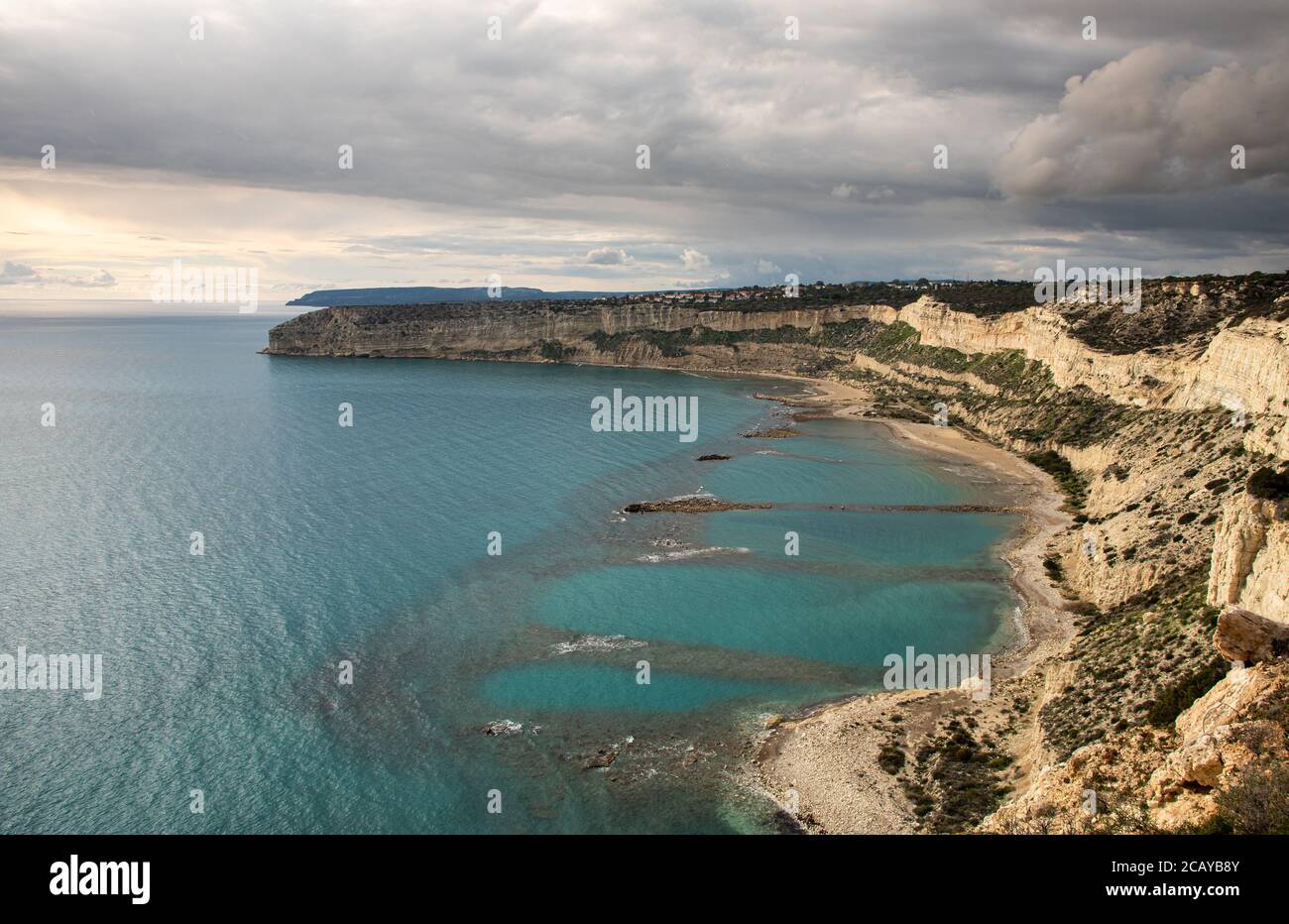 Coastal rocky seascape with cliffs and sea with cloudy stormy sky at sunset. Stock Photo