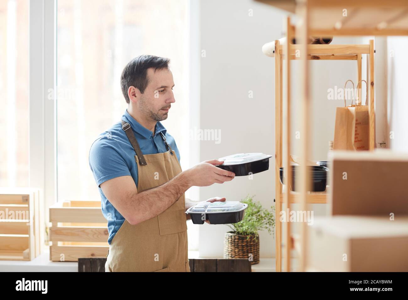Side View Portrait Of Mature Man Wearing Apron Stacking Plastic side-view-portrait-of-mature-man-wearing-apron-stacking-plastic