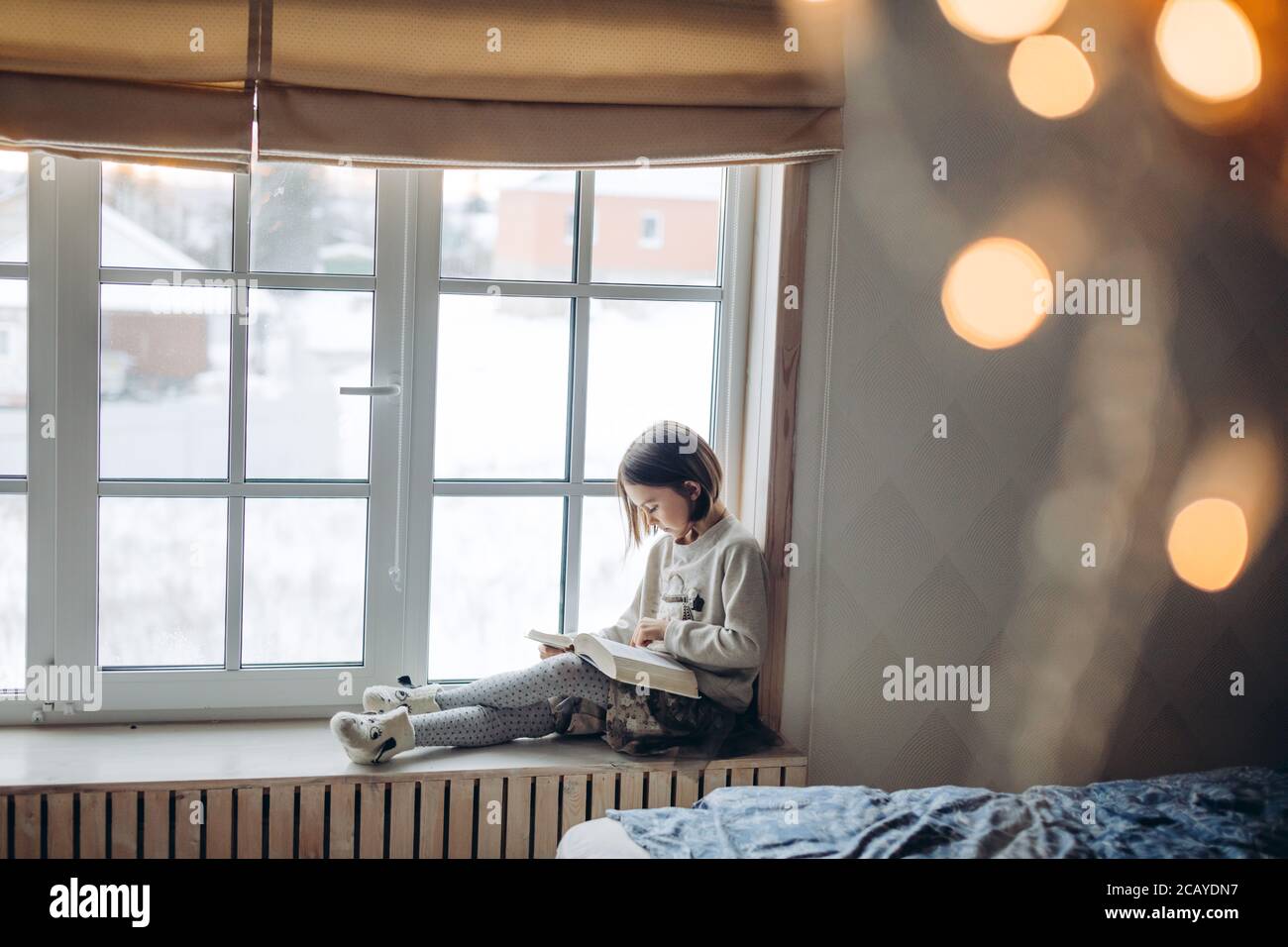 cute little girl with a book. side view photo. pleasant adorable girl is concentrated on reading her favourite book Stock Photo