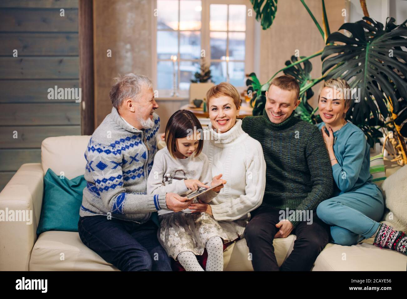 little girl is holding photo album in her hands while her relatives are smiling. close up shot. Stock Photo