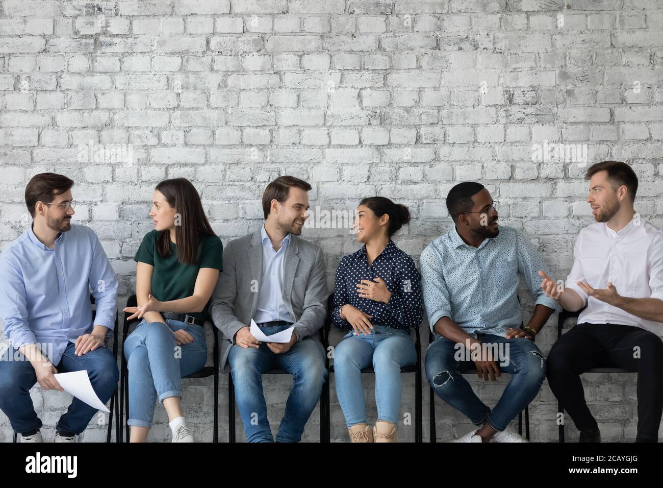 Young diverse candidates chatting, talking while waiting for job interview Stock Photo