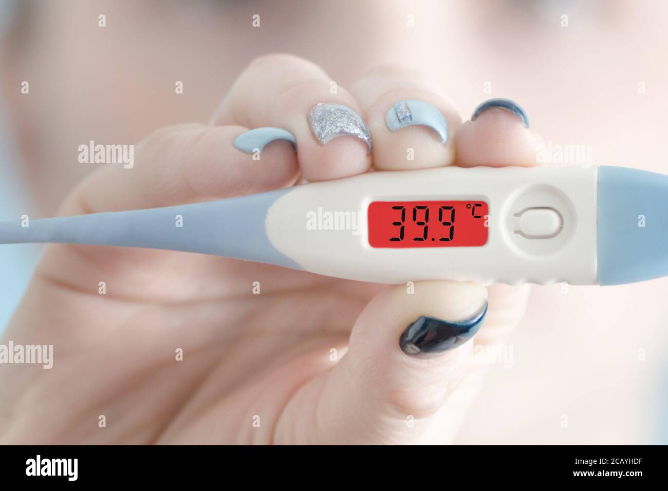 Thermometer in female hand. Hyperthermia. Face on background Stock Photo