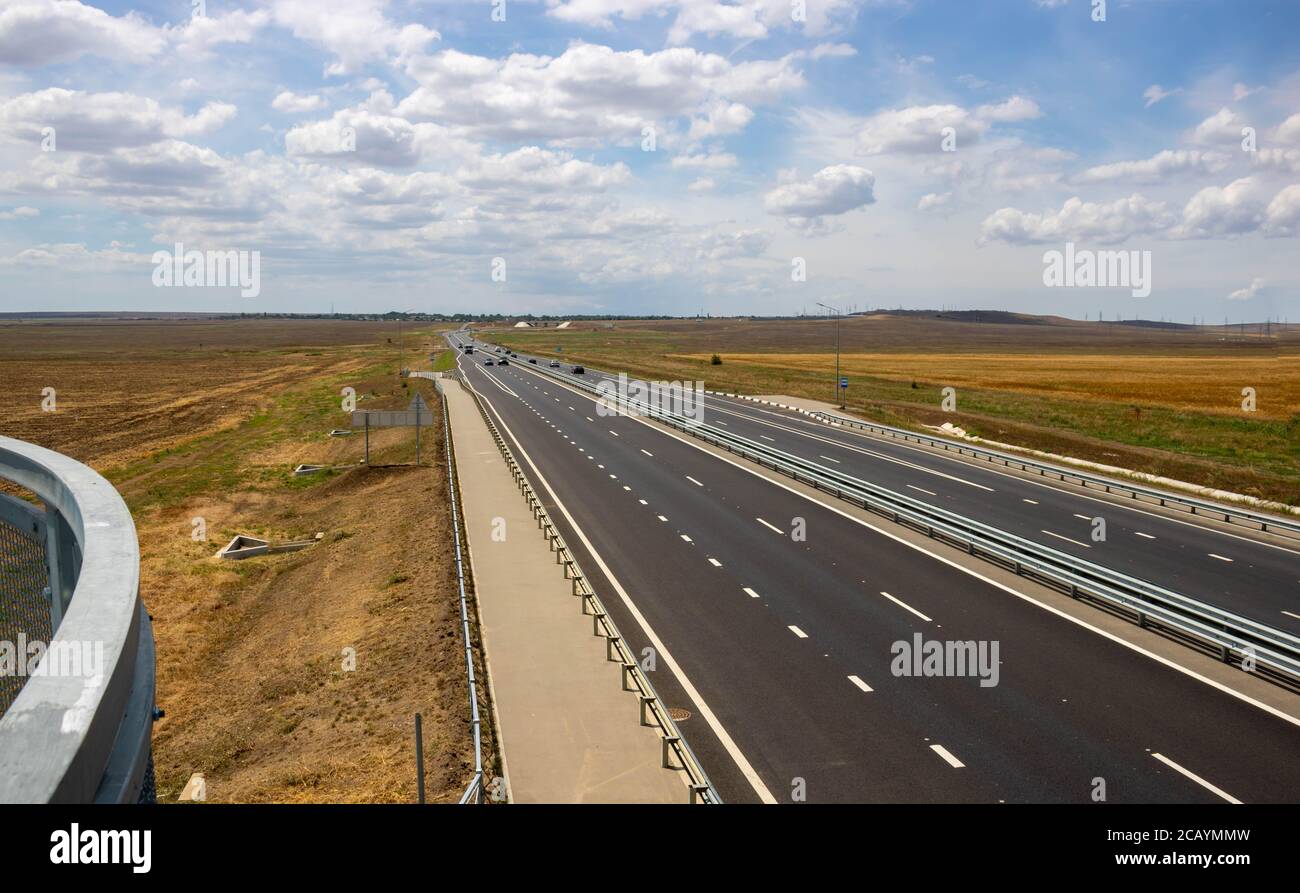 highway in steppe against a blue sky,long road stretching out into the distance. Stock Photo