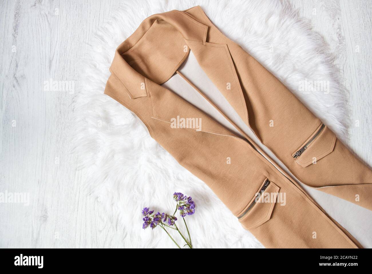 Brown jacket without sleeves on white fur. Close up. Fashionable